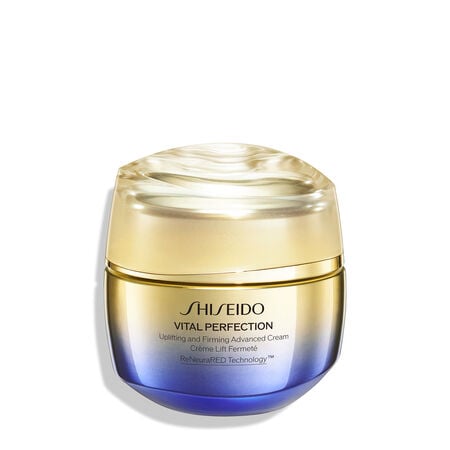 Un frasco redondo, dorado y morado de la crema Shiseido Vital Perfection Uplifting and Firming Advanced. El frasco cerrado lleva el logotipo de Shiseido,, el nombre del producto, y las palabras "ReNeuraRED Technology."