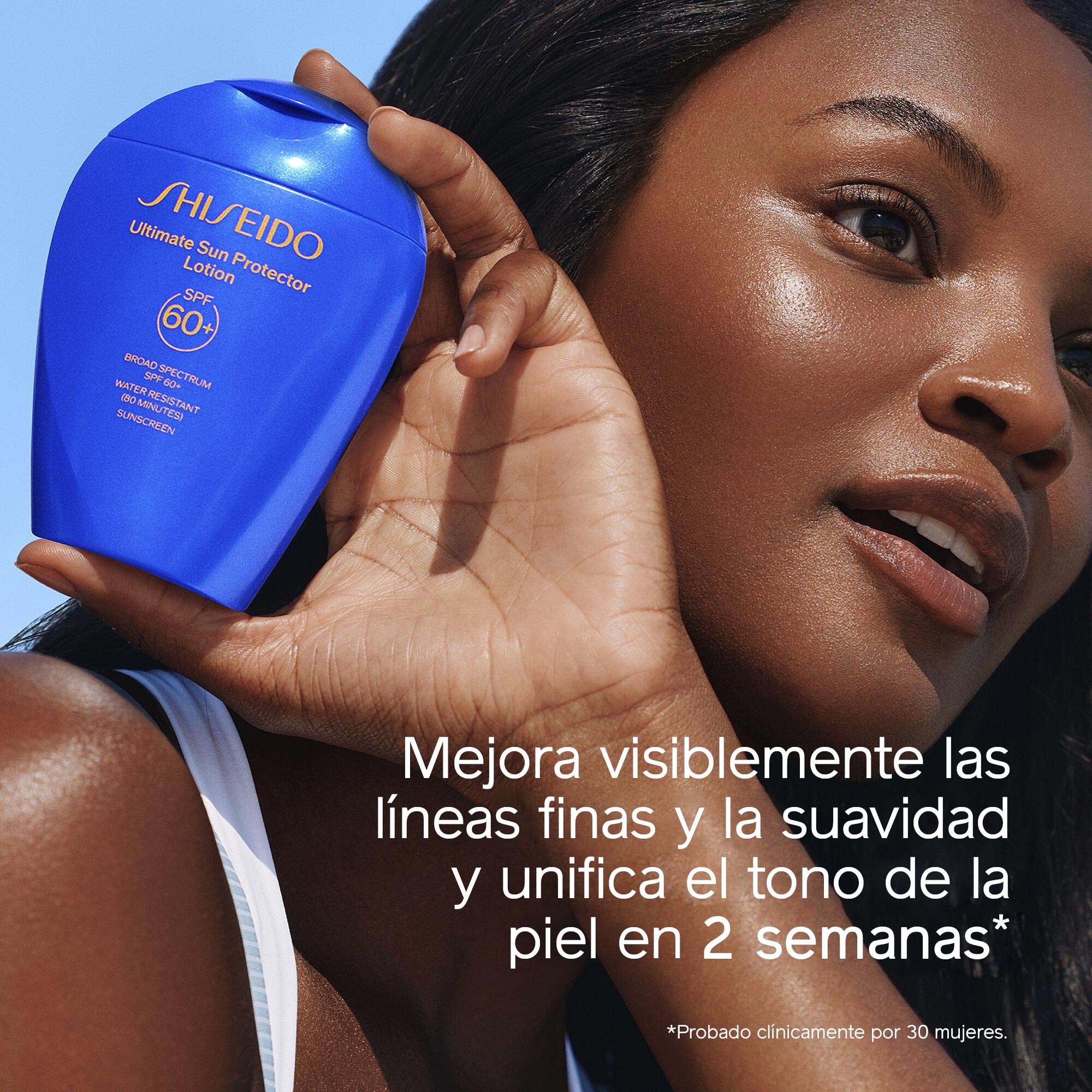 Una mujer con la piel luminosa sostiene un frasco azul de Shiseido Ultimate Sun Protector Lotion SPF 60+ cerca del rostro. El texto superpuesto dice lo siguiente: Mejora visiblemente las líneas finas y la suavidad, y unifica el tono de la piel en 2 semanas.